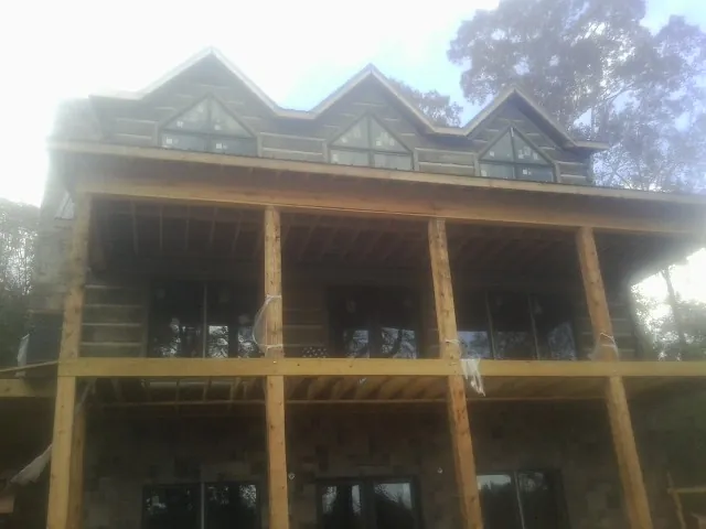 Dormers and porch framing on a large log home under construction — Roof Coating work by our crew in Fremont